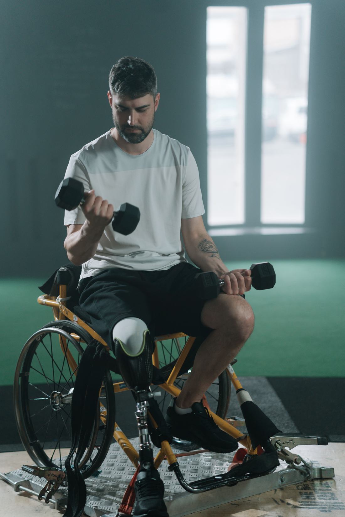 Fiatal férfi sportkerekesszékben súlyzózik az edzőteremben